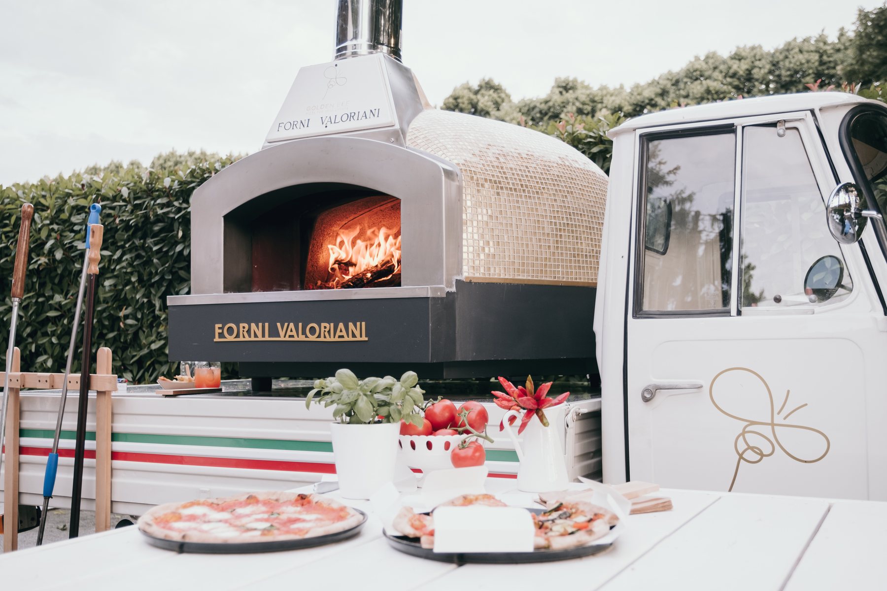 Forno a legna Valoriani in mosaico foglia oro acceso di sera, montato sull'Ape Piaggio Golden Bee