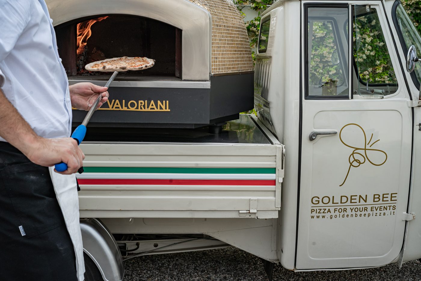 Forno a legna Golden Bee acceso di sera con luci, allestimento per evento serale