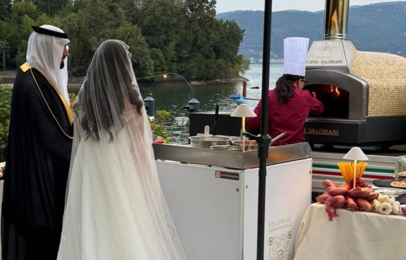 Pizzaiolo sforna una pizza dal forno a legna a bordo dell'Ape Piaggio Golden Bee
