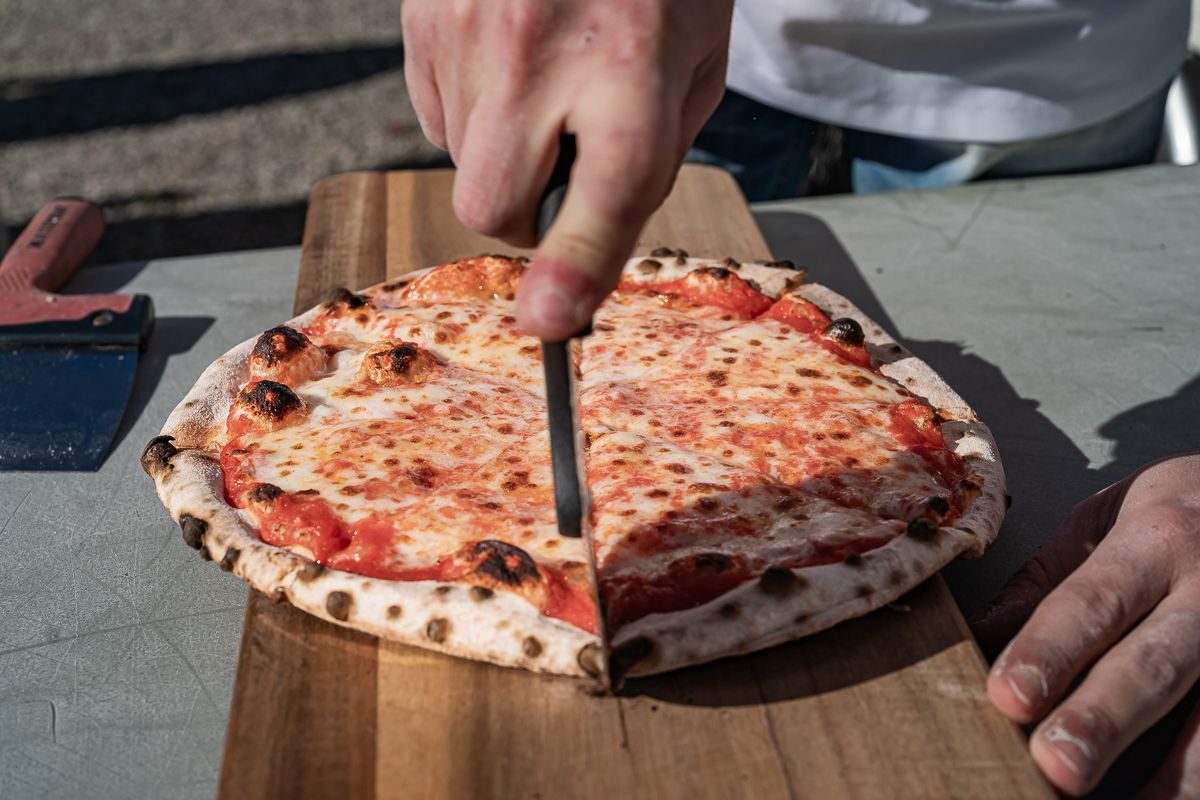 Due pizzaioli Golden Bee in divisa servono pizza durante un evento serale